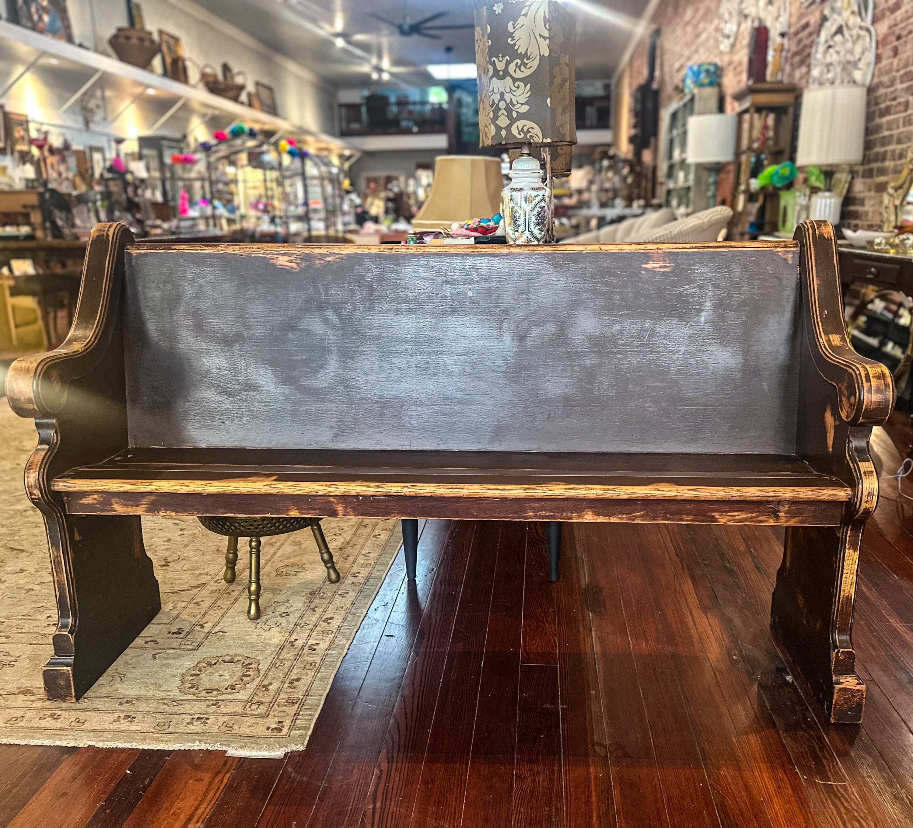 Wooden pew in a store with various items on shelves in the background